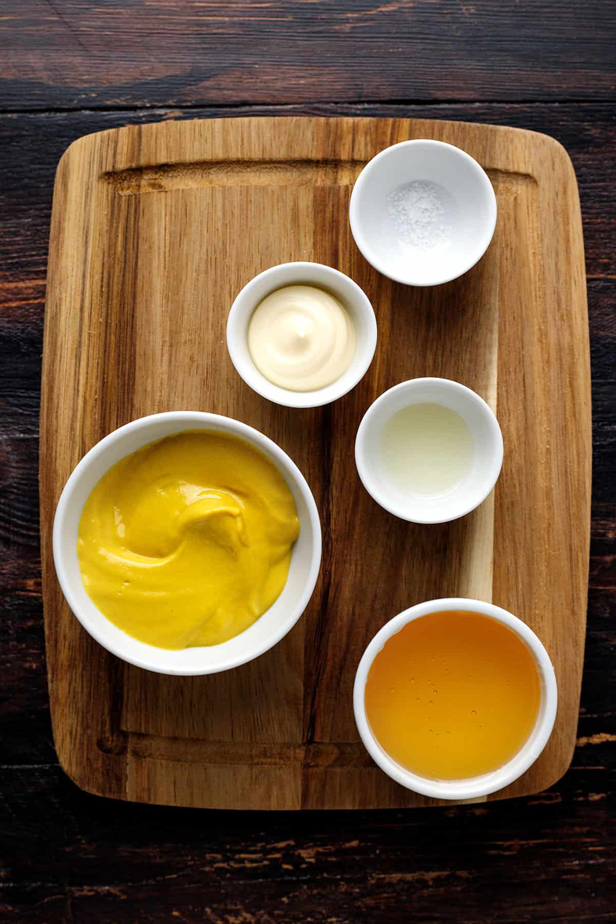 Ingredients for Honey-Mustard Sauce - on a wooden cutting board.