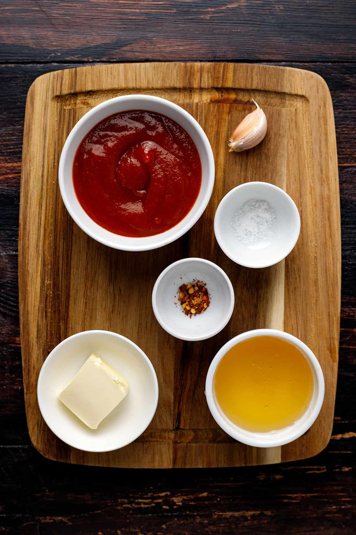 Ingredients for honey sriracha sauce - on a wooden cutting board.