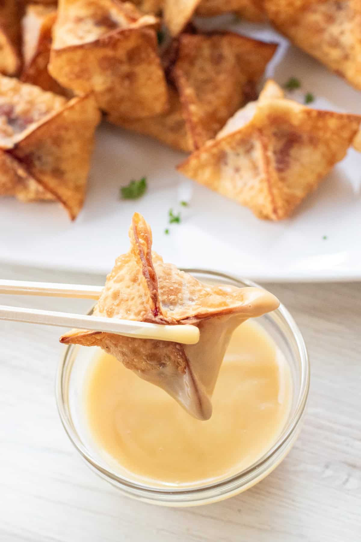 chopsticks holding a gravy dipped wonton.