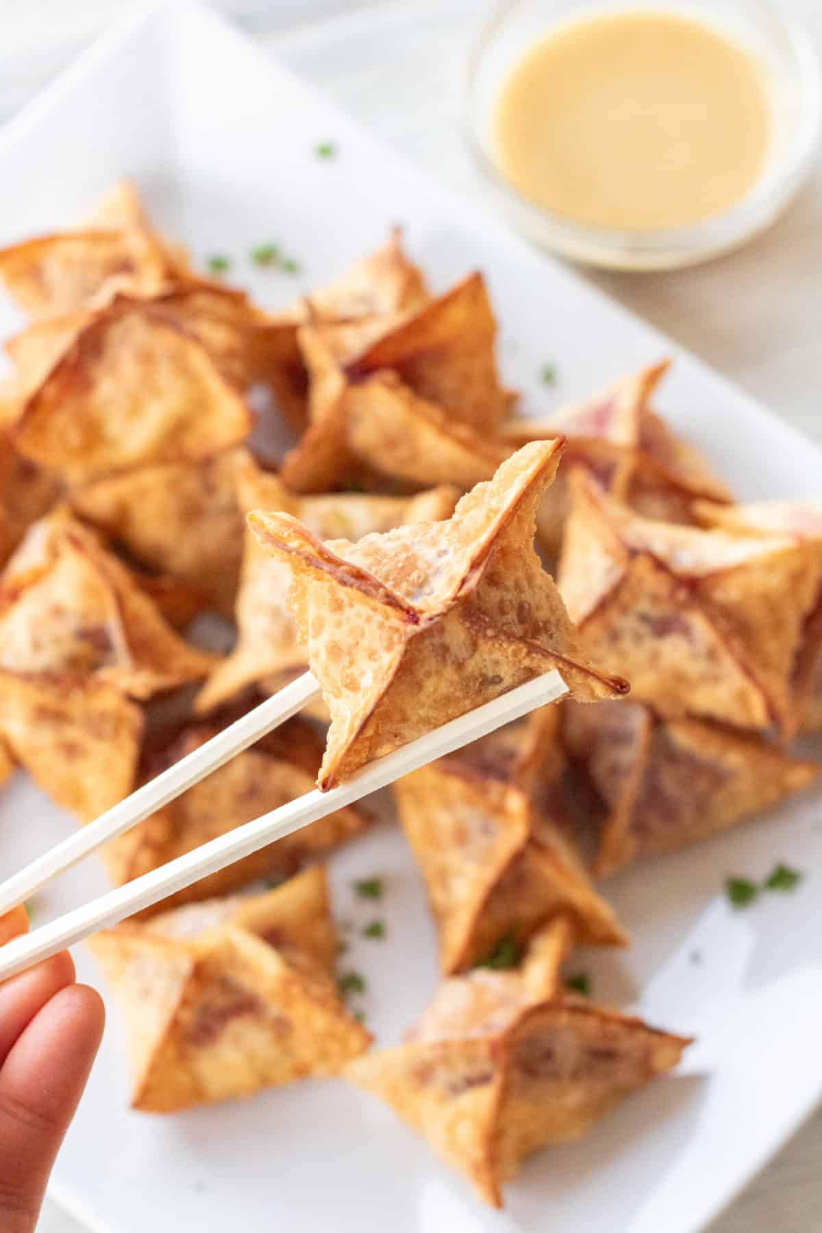 chopsticks holding up a fried wonton.