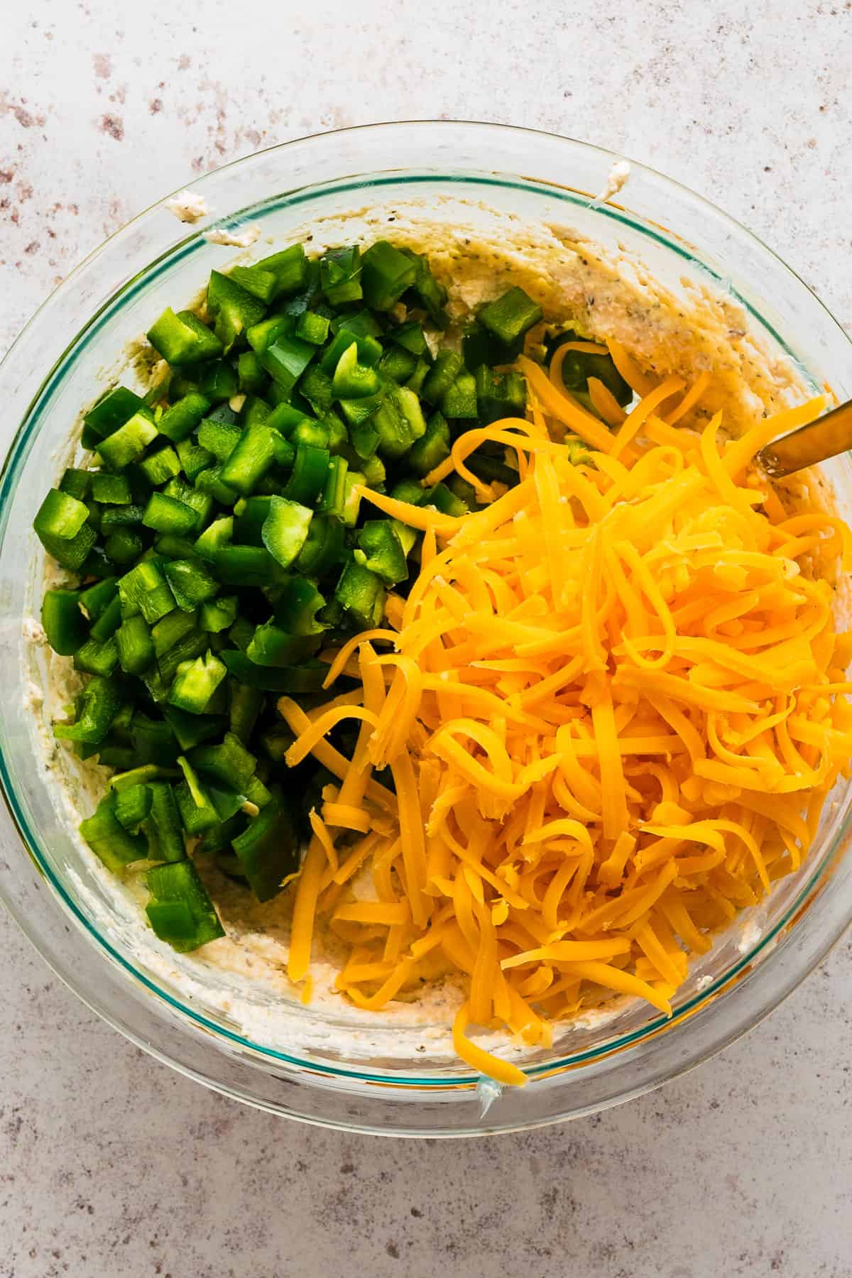 add diced jalapenos and shredded cheddar cheese to the dip in a bowl.