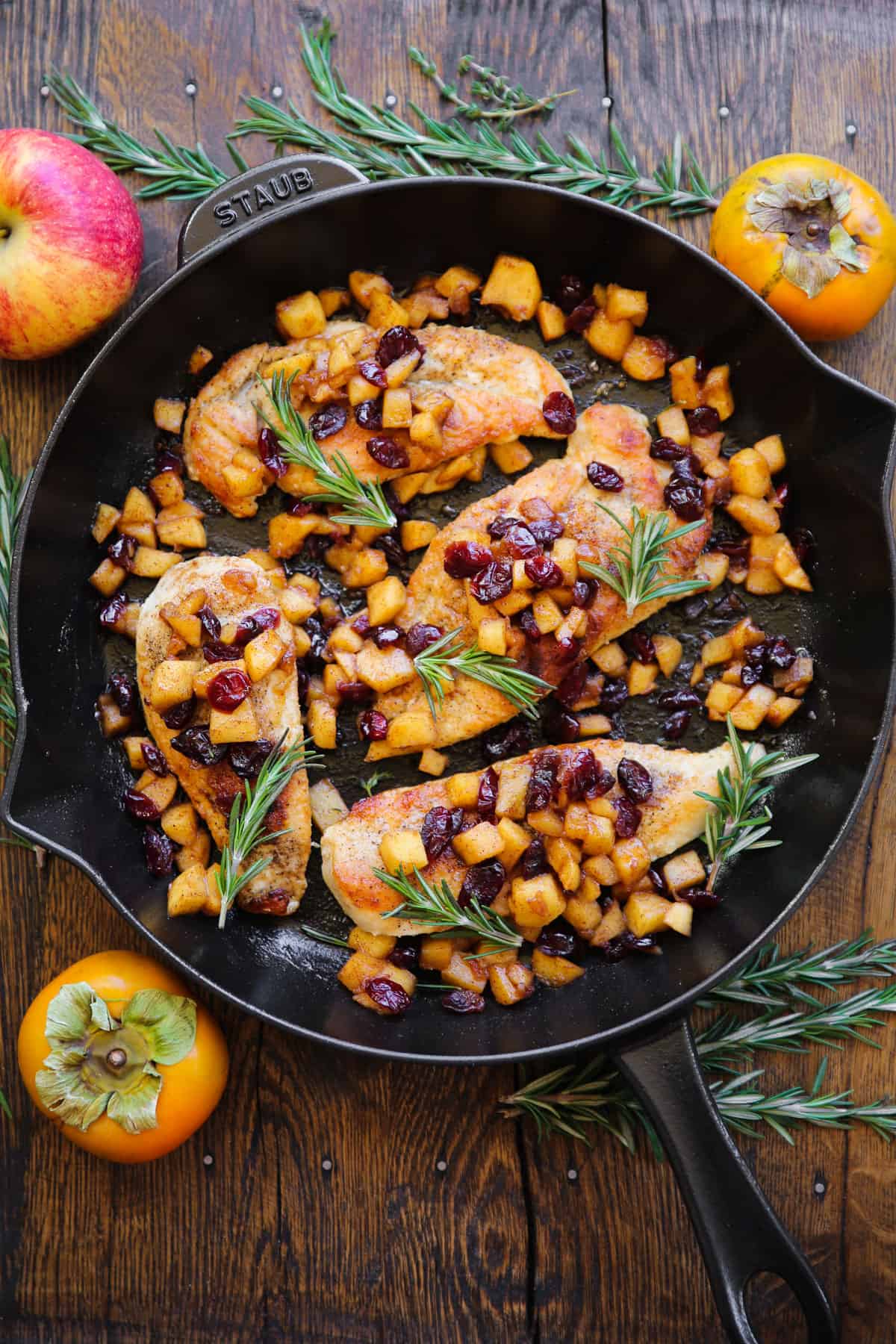pan-seared chicken breasts with cooked cubed apples, dried cranberries, and cinnamon-honey glaze - in a cast iron skillet.