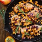 pan-seared chicken breasts with cooked cubed apples, dried cranberries, and cinnamon-honey glaze - in a cast iron skillet.