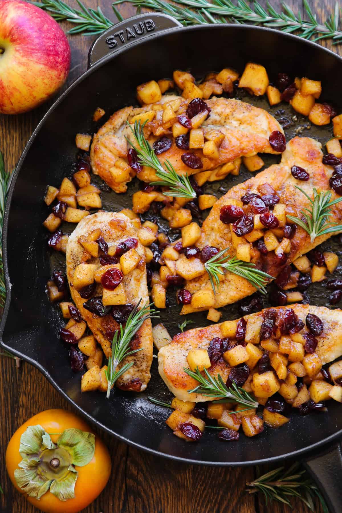 pan-seared chicken breasts with cooked cubed apples, dried cranberries, and cinnamon-honey glaze - in a cast iron skillet.