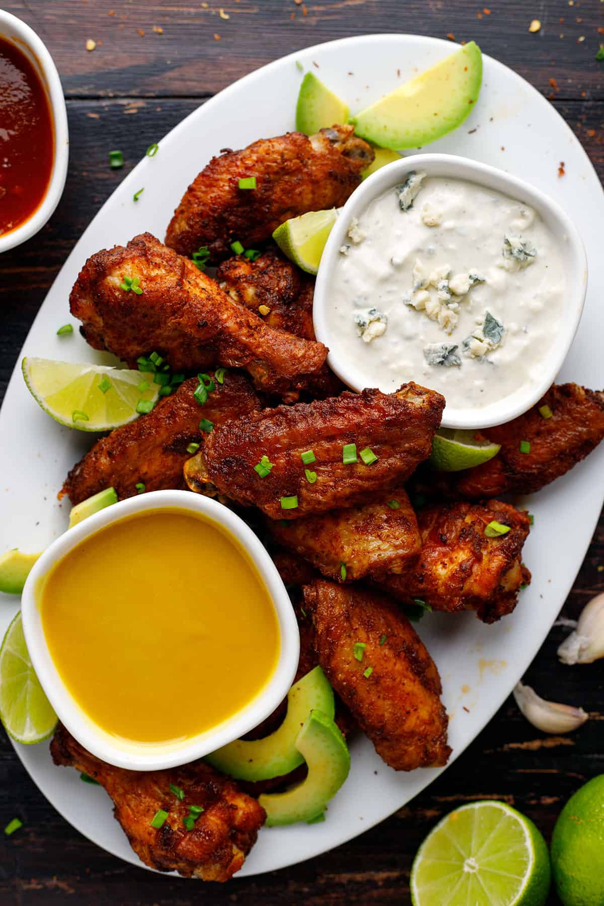 Baked chicken wings with 2 sauces (blue cheese and honey-mustard) in small bowls - on a sheet pan.
