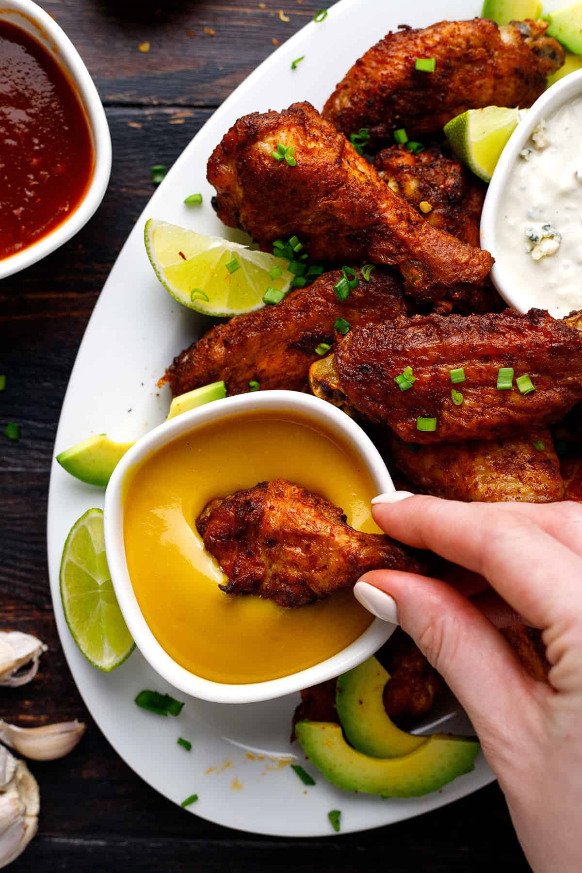 baked chicken wings and and a small bowl of honey mustard sauce - on a white plate.
