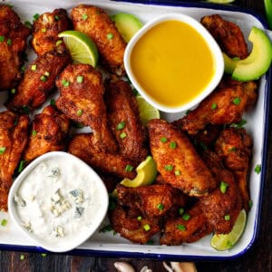 Baked chicken wings with 2 sauces (honey-mustard and blue cheese) on a sheet pan.