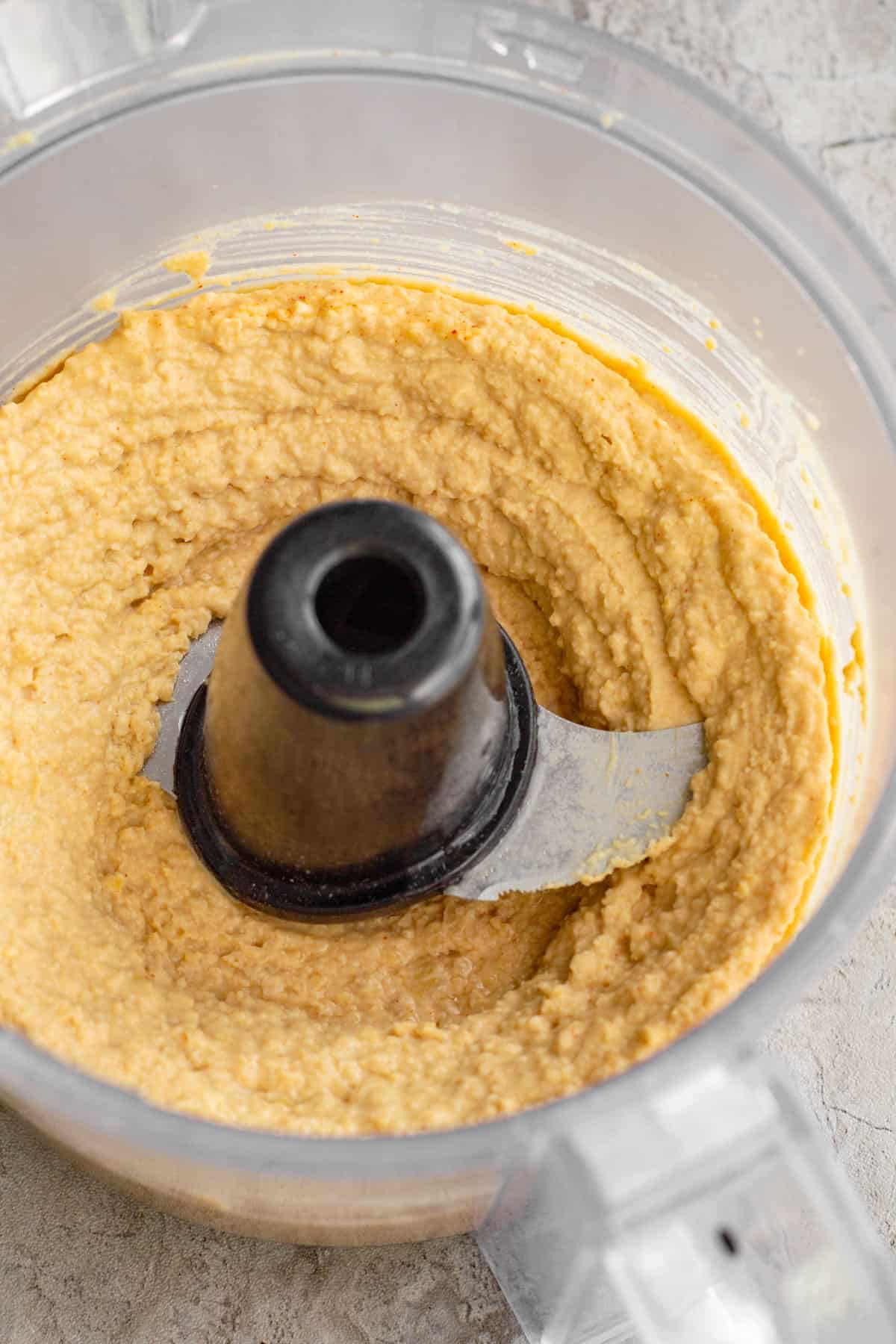 blended ingredients for buffalo hummus in a food processor.