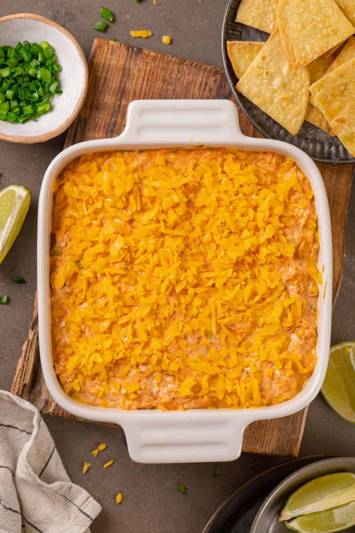 buffalo chicken dip topped with shredded Cheddar cheese in a baking dish.