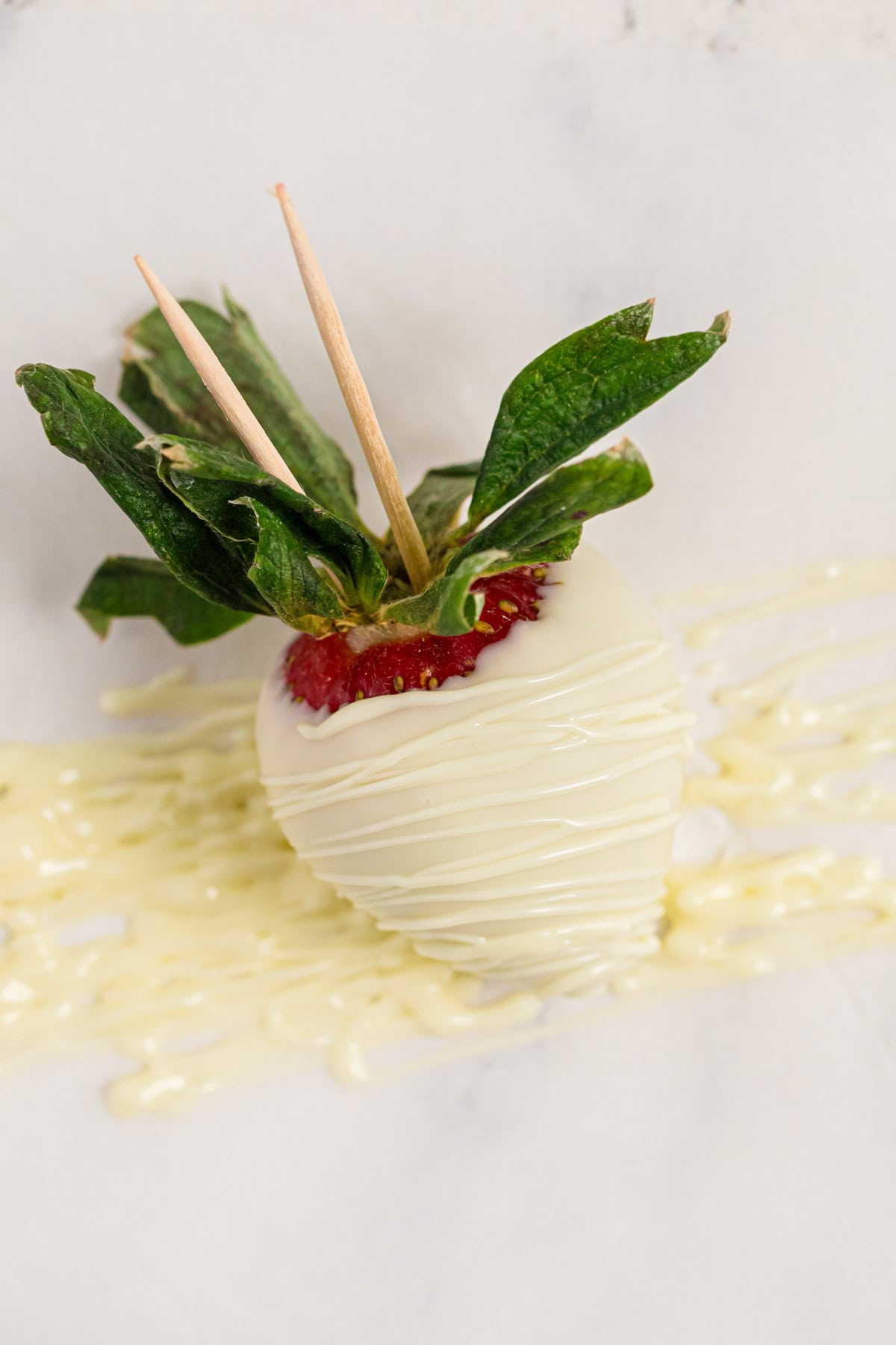 Drizzling melted white chocolate over a strawberry.