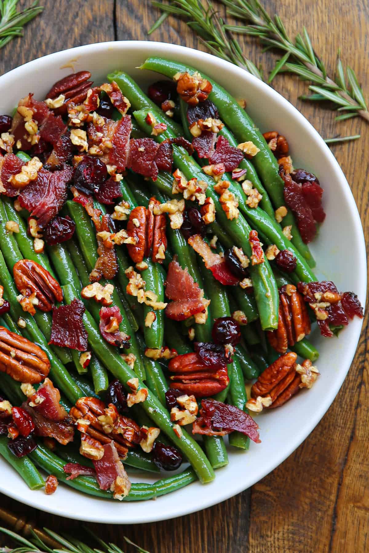 Green bean salad with bacon, pecans, dried cranberries - in a white bowl.