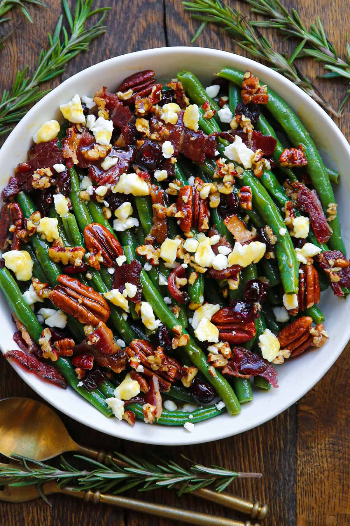 Green bean salad with bacon, pecans, dried cranberries, feta cheese - in a white bowl.