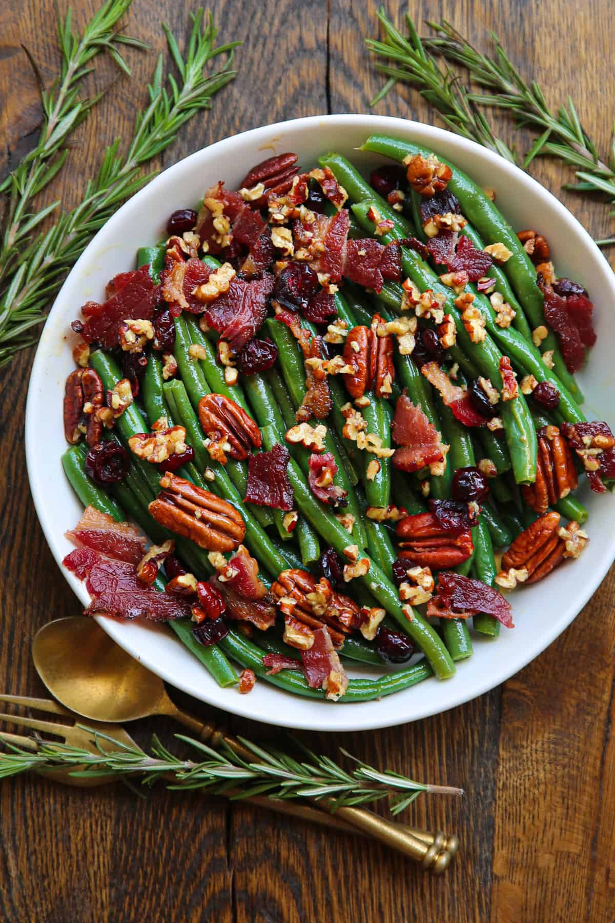 Green bean salad with bacon, pecans, dried cranberries - in a white bowl.