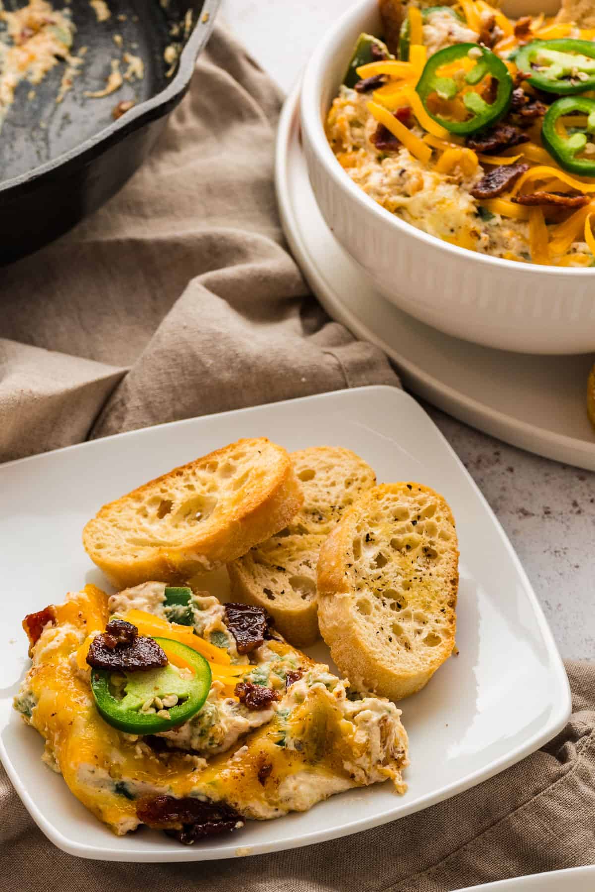 Jalapeno popper dip with bread slices on a plate.
