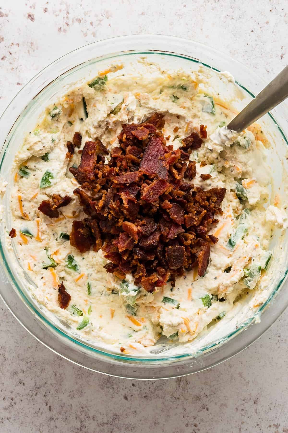 jalapeno popper dip with crumbled bacon in a bowl.