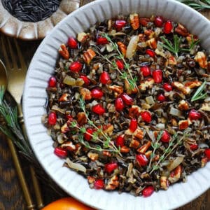 pecan wild rice with pomegranate and fresh herbs - in a white bowl.