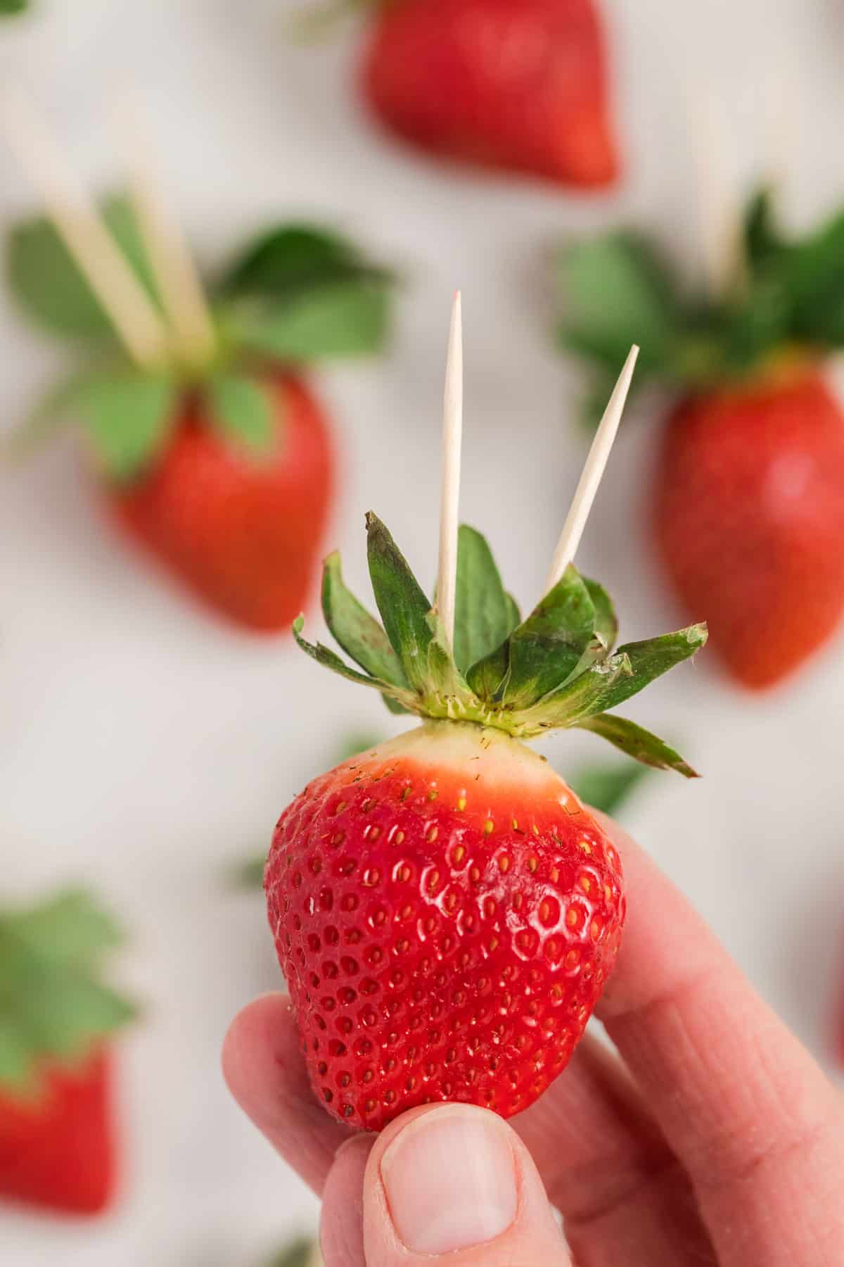 Strawberry with two inserted toothpicks.
