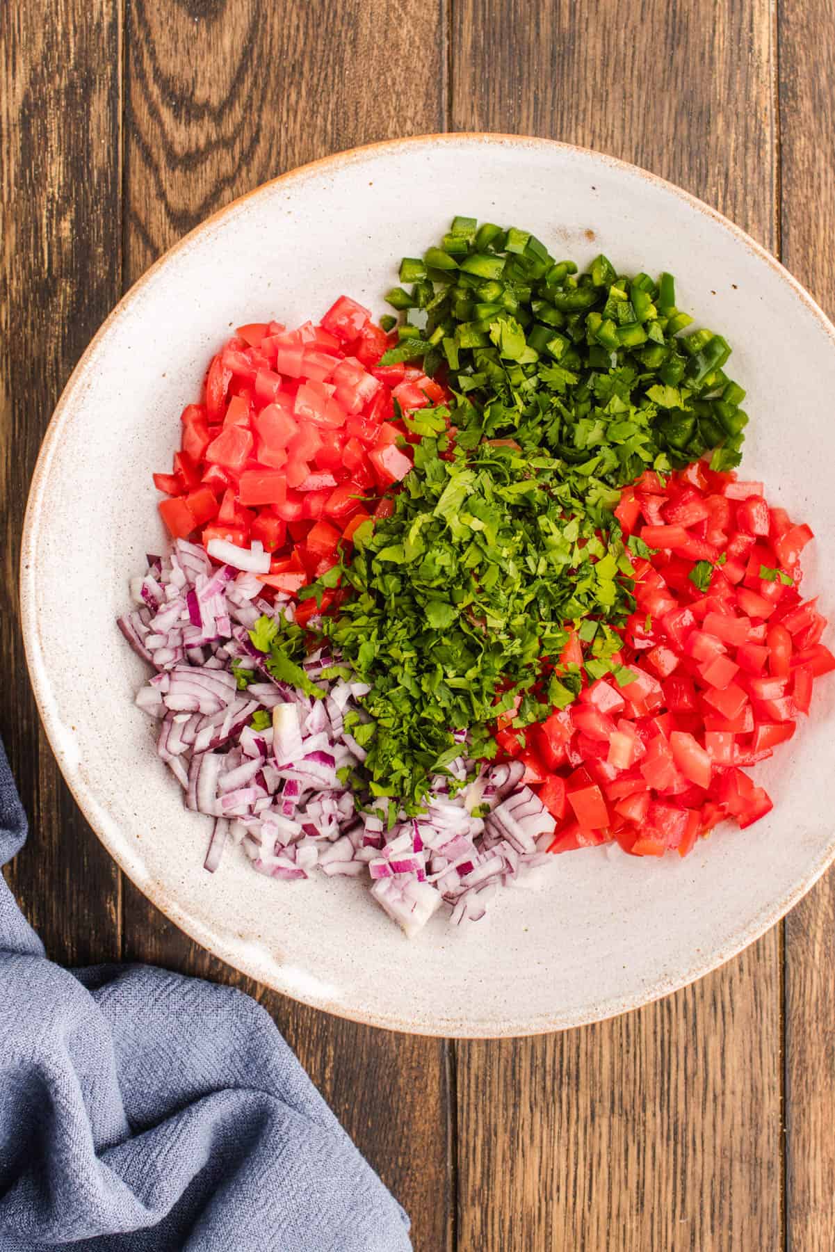 The Ingredients for Pico De Gallo All chopped up ingredients for Pico De Gallo in sections in a bowl.