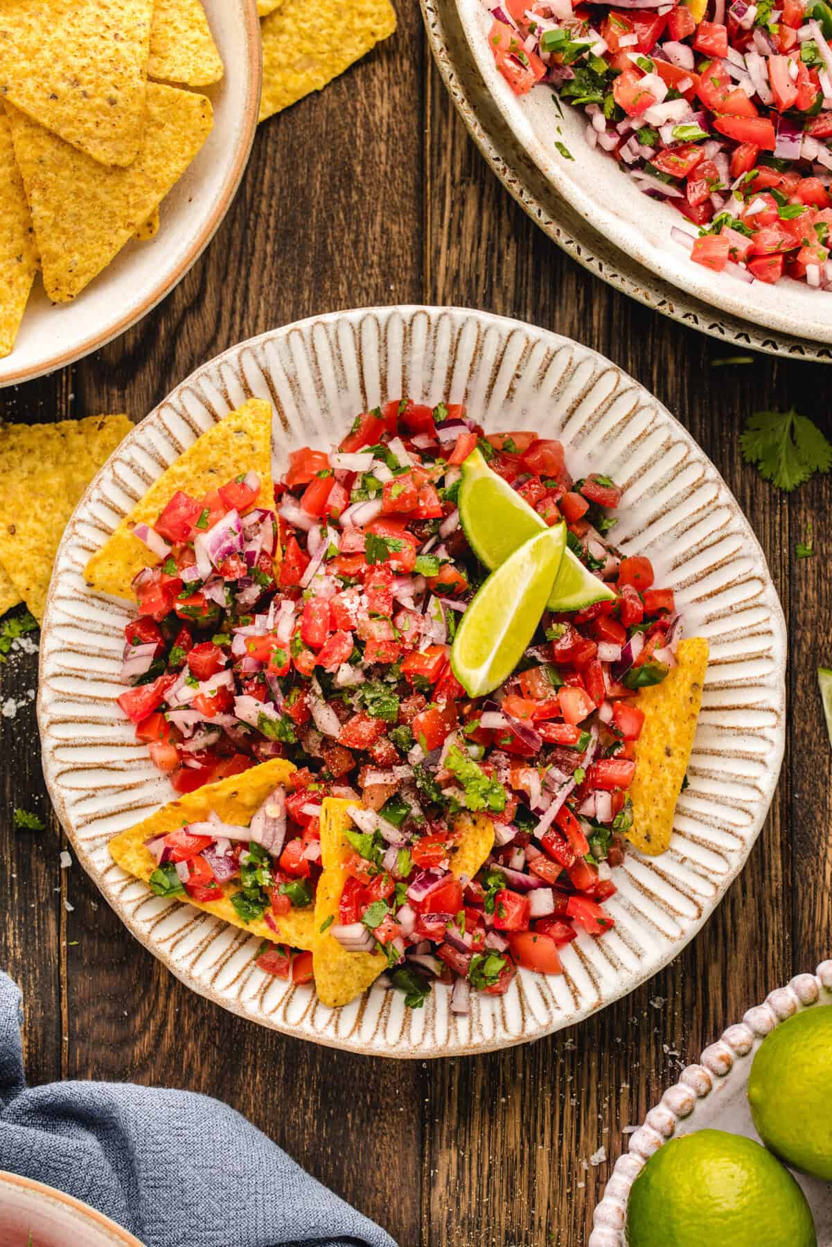 Pico De Gallo Pico De Gallo with tortilla chips and lime slices - in a bowl.