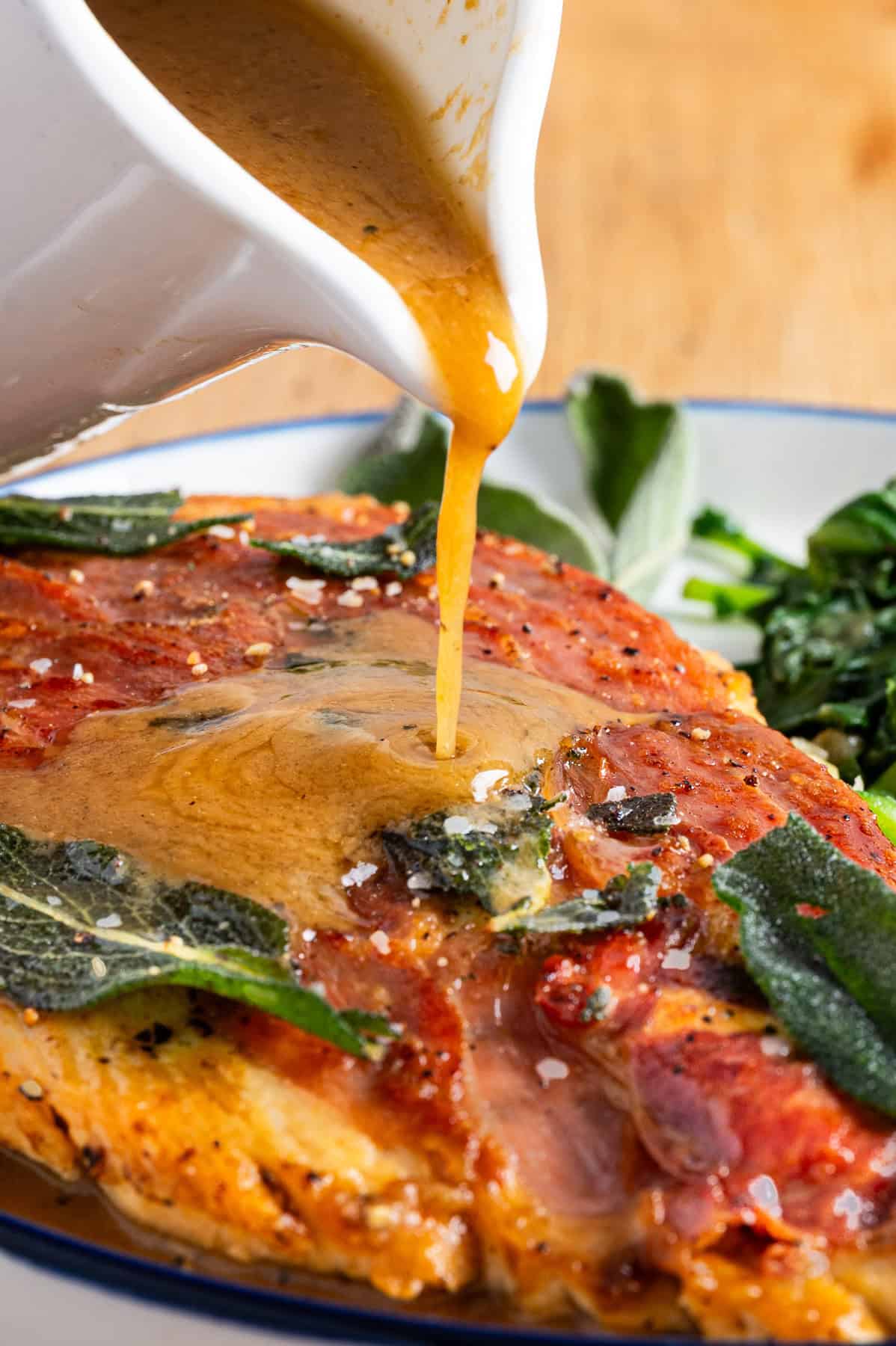 Chicken Saltimbocca with the sauce being poured over it on a plate.