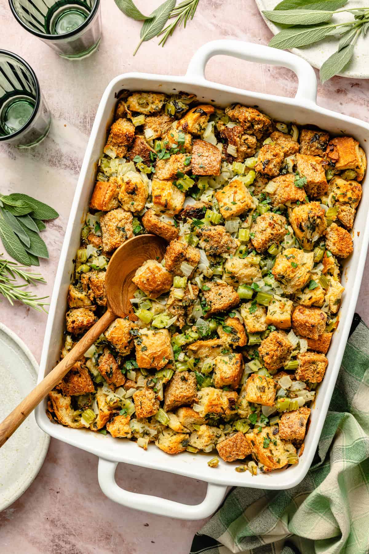homemade stuffing with butter and herbs in a white casserole dish.