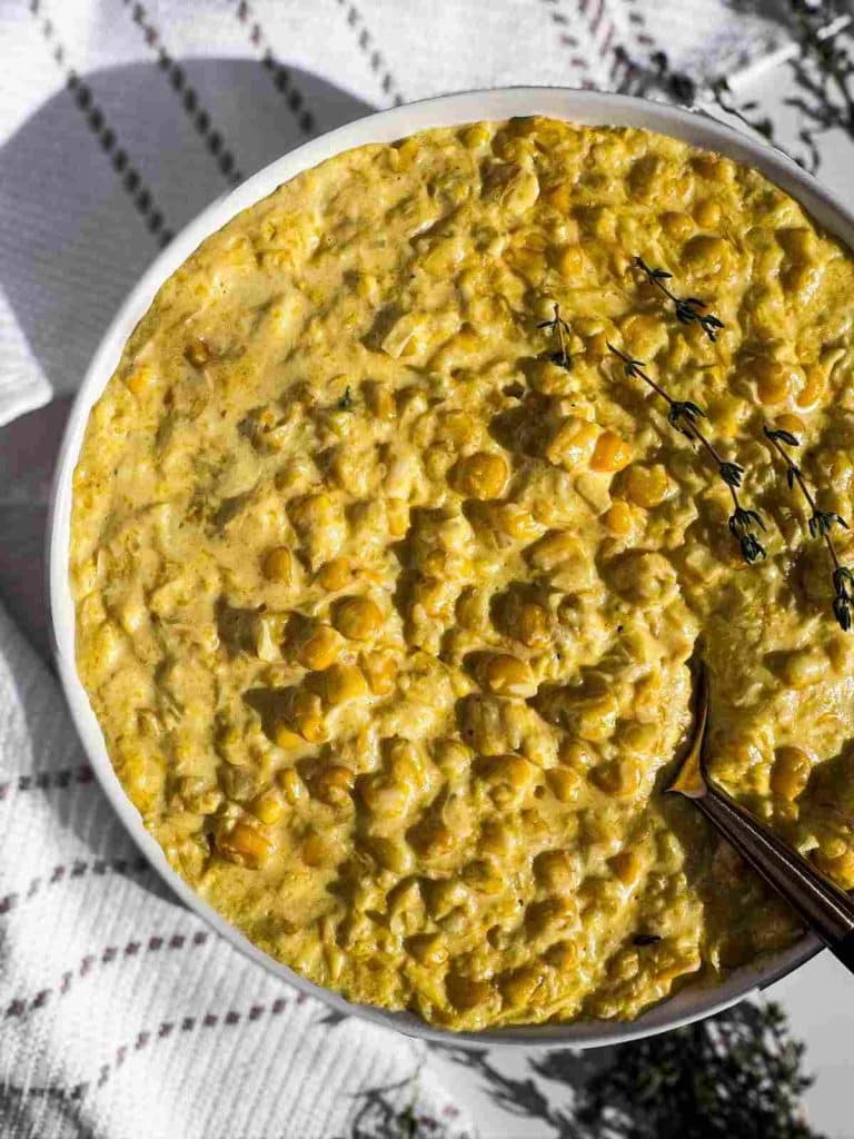 Creamed Corn in a bowl topped with thyme