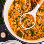 Vegetable Barley Soup with Carrots, Mushrooms, Kale, Tomatoes, and Chickpeas - in a white soup pot.