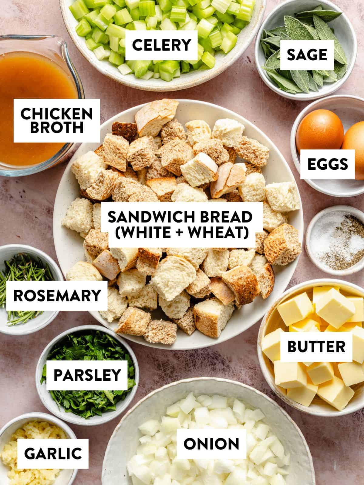 dried bread cubes, fresh poultry herbs, butter, onion, celery, broth, and eggs on a counter.